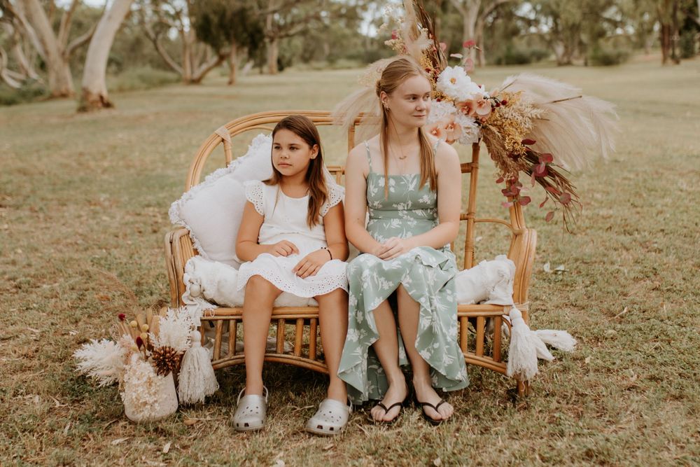 sisters sitting on cane chair looking into the distance