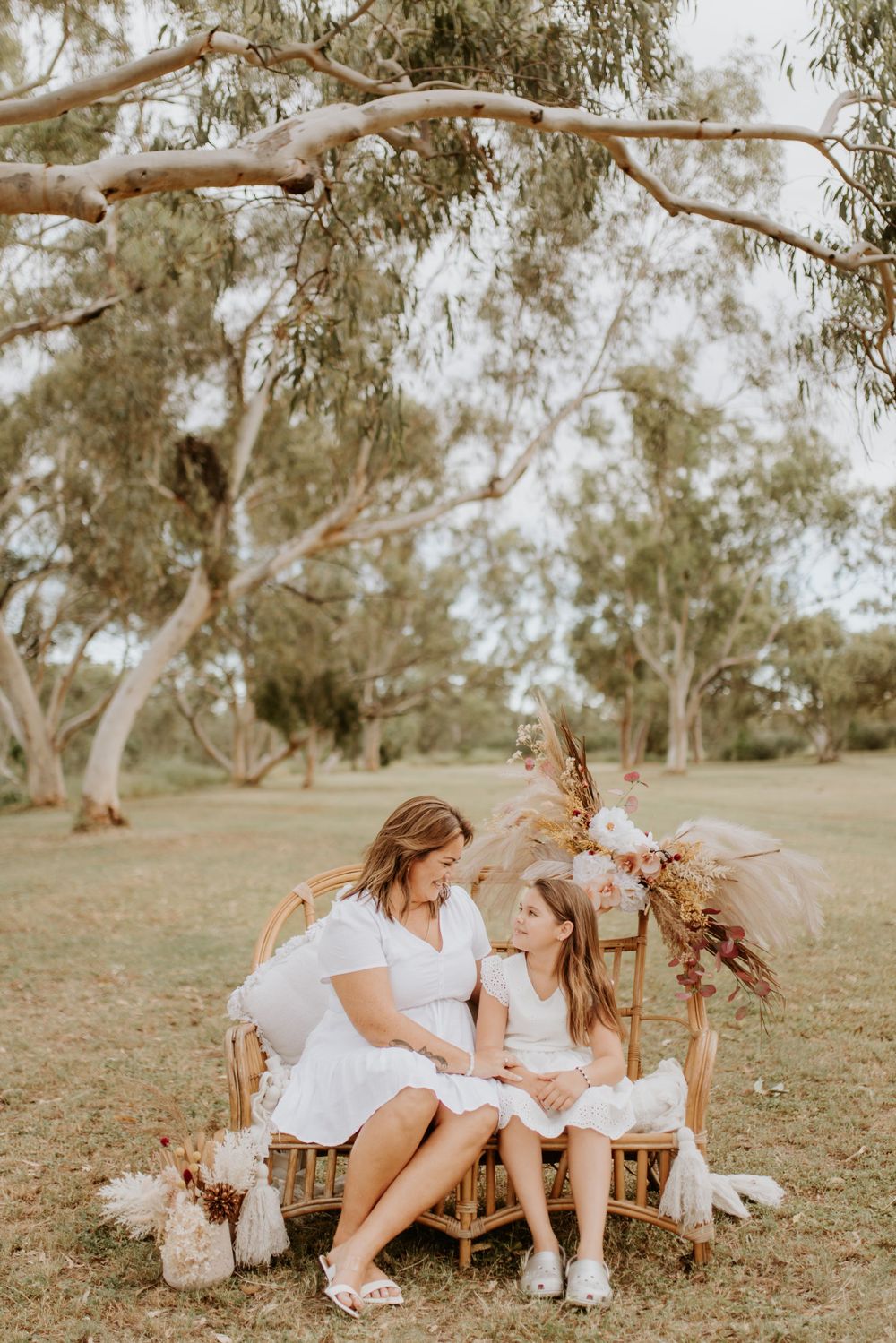 mother and daughter sitting on cane chair in the park in mount isa