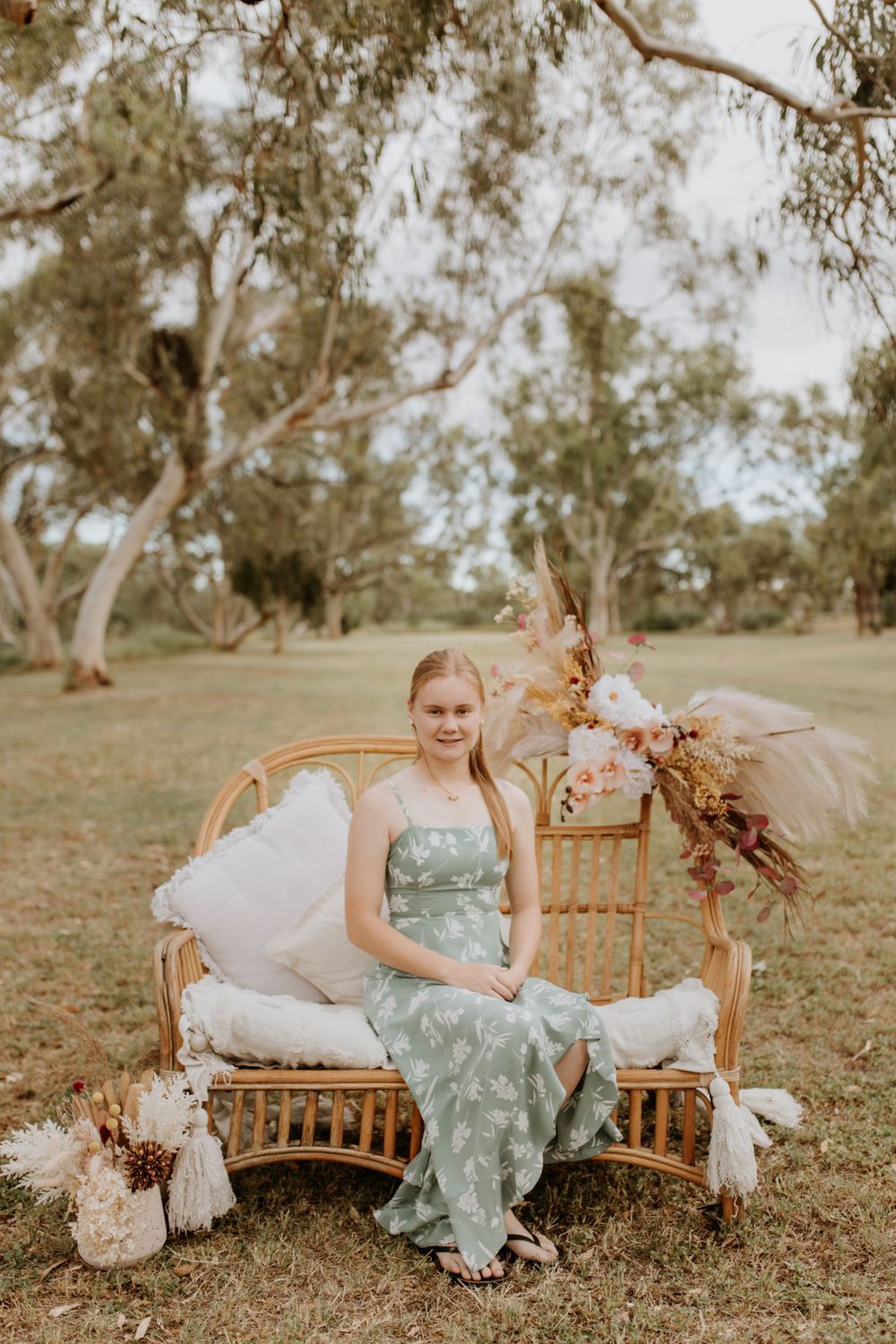 young girl smiles at the camera while sitting on cane chair