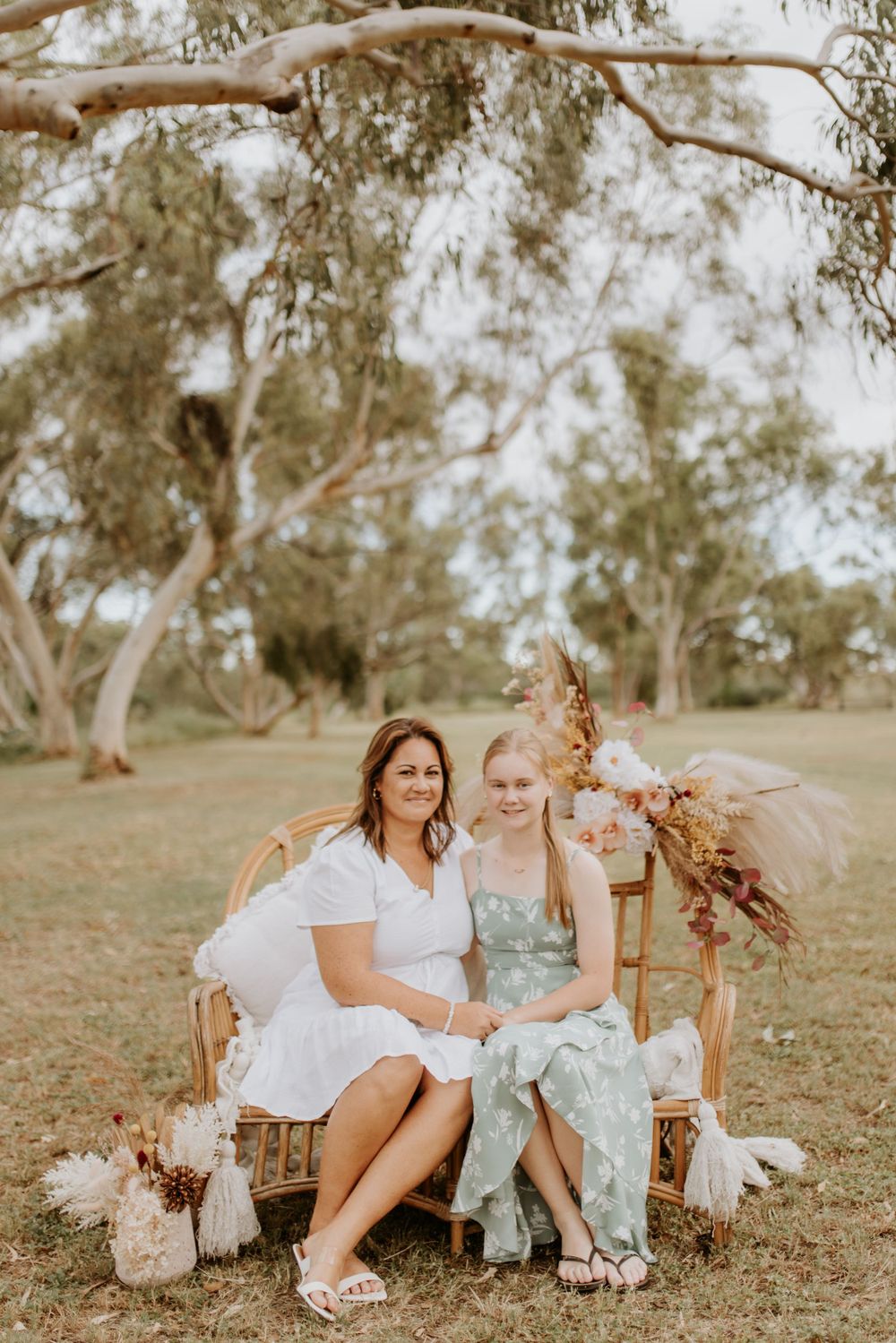 mother and daughter sitting on cane chair in the park in mount isa