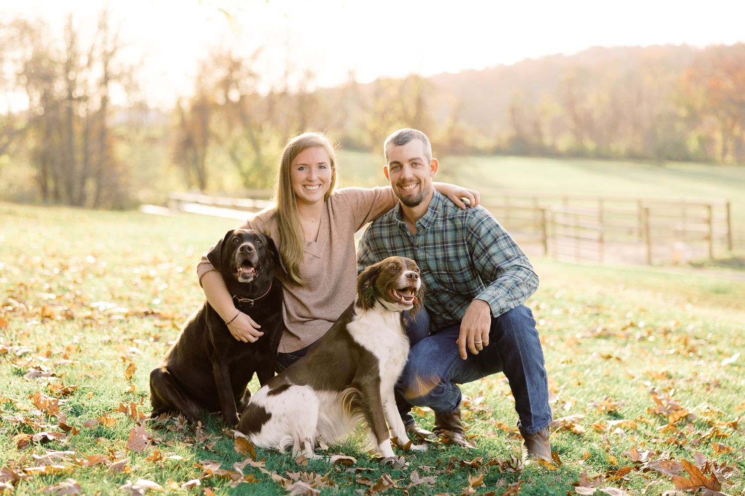 Family portrait outdoors with two dogs on an autumn day with fallen leaves.