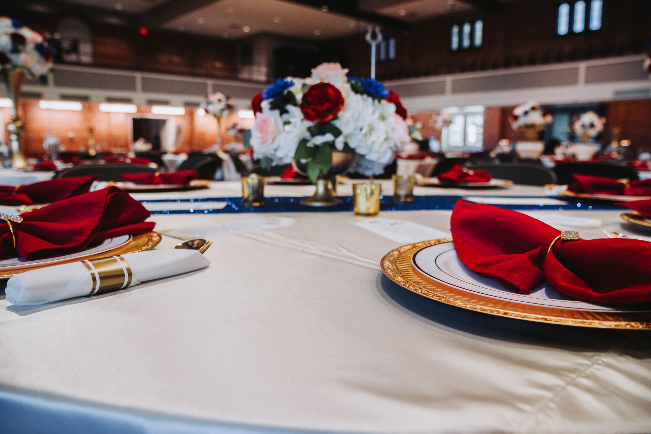 Elegant table setting with red napkins and centerpieces for formal event.