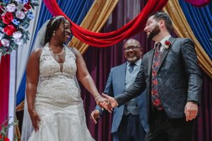A joyous wedding ceremony moment captured under elegant red and blue draped decor.