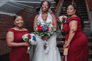 Wedding party featuring bridesmaids in red dresses holding blue and white bouquets.