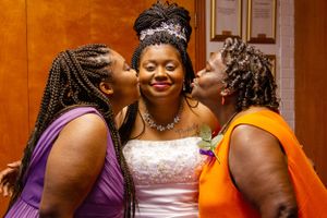 Joyful candid moment between three women at a formal event.