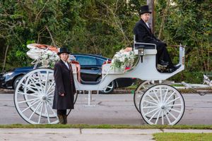 Elegant white horse-drawn carriage with coachmen in formal attire.