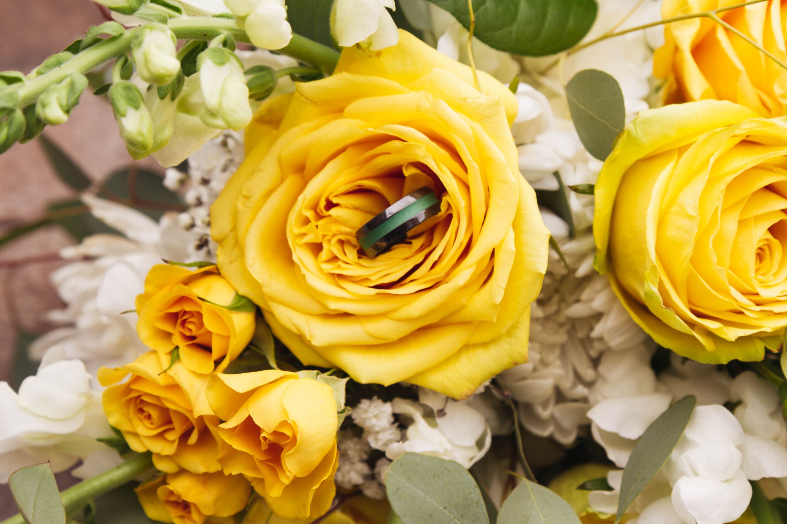 Close-up of yellow roses and white flowers in a wedding bouquet arrangement.