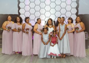 Bridal party in soft pink dresses posing against a modern hexagon backdrop.