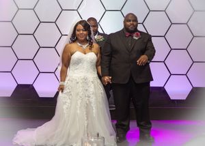 Wedding couple standing in front of a modern hexagonal backdrop with purple lighting.
