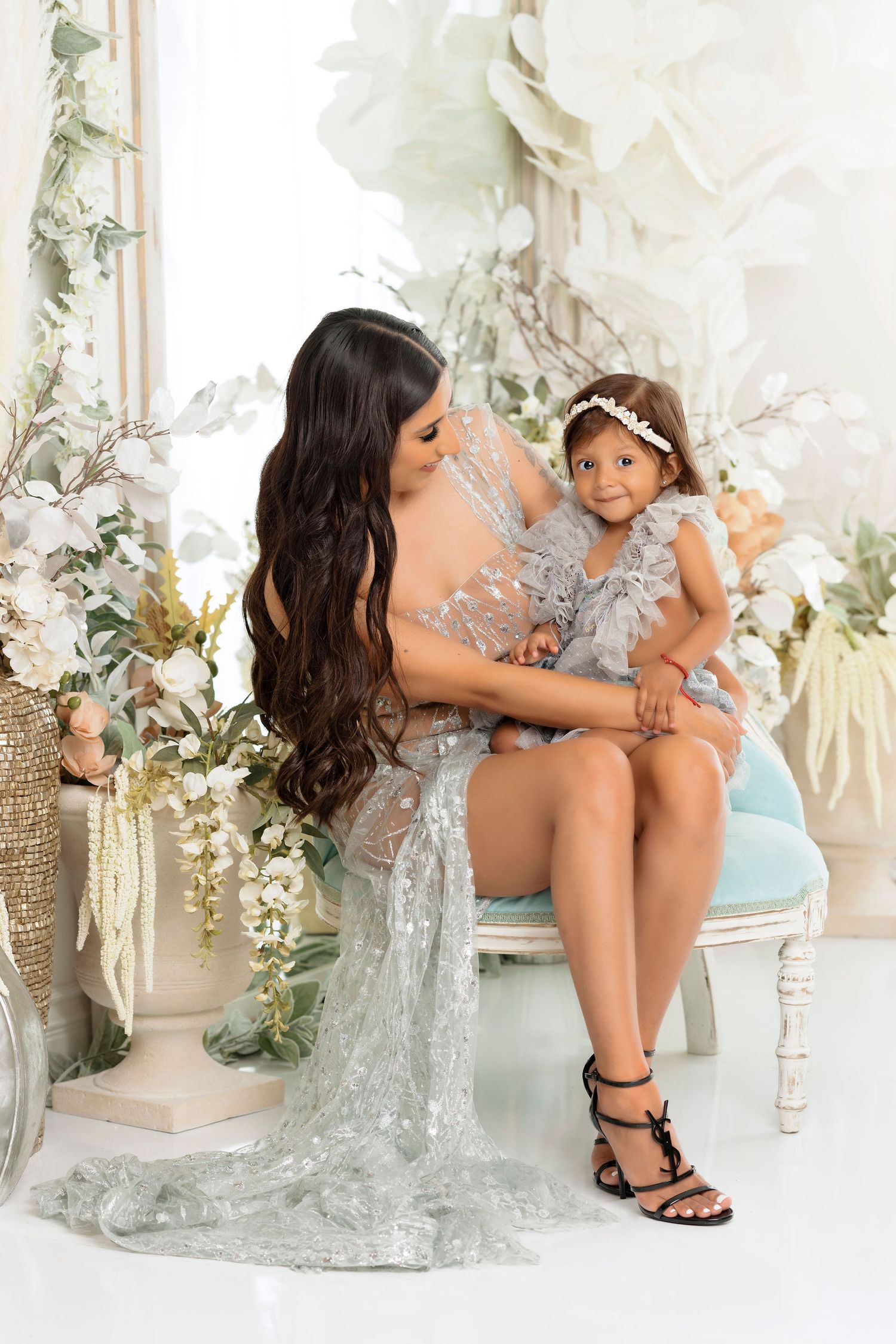 Elegant portrait with floral decorations and a silver sequined gown in a light-filled studio setting.