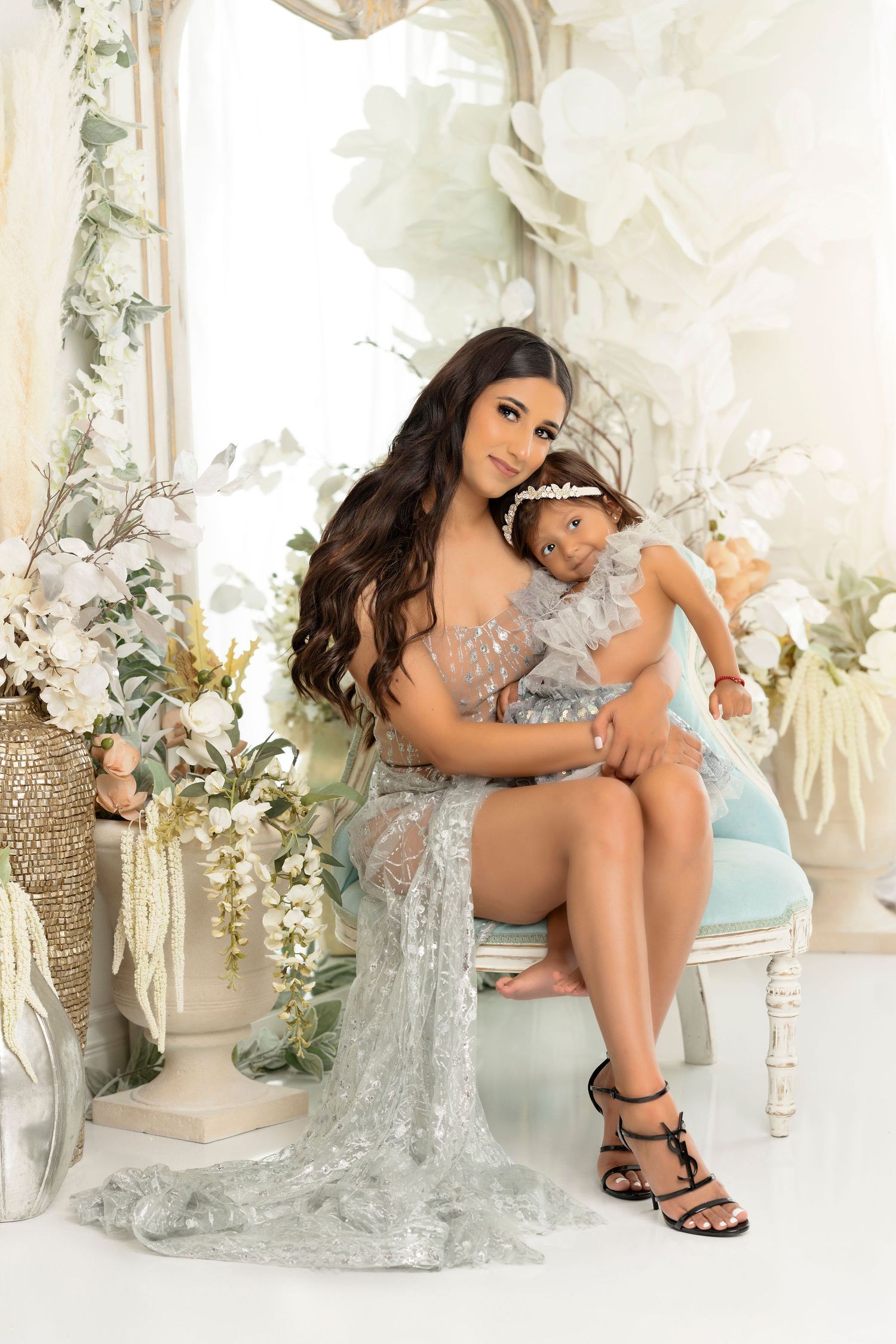 Intimate studio portrait with white floral arrangements and delicate silver gown details.