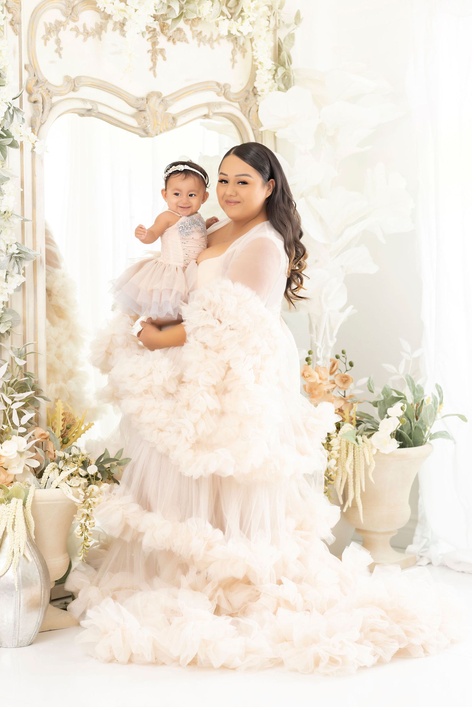 Dreamy portrait with ruffled peach gown against floral decorated backdrop.