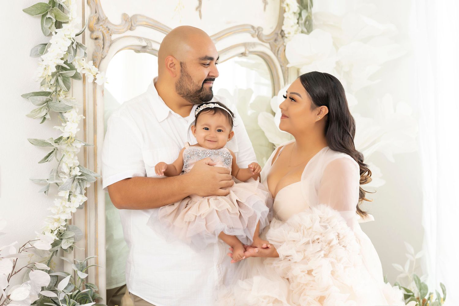 Romantic family portrait with floral arch and delicate greenery decorations.