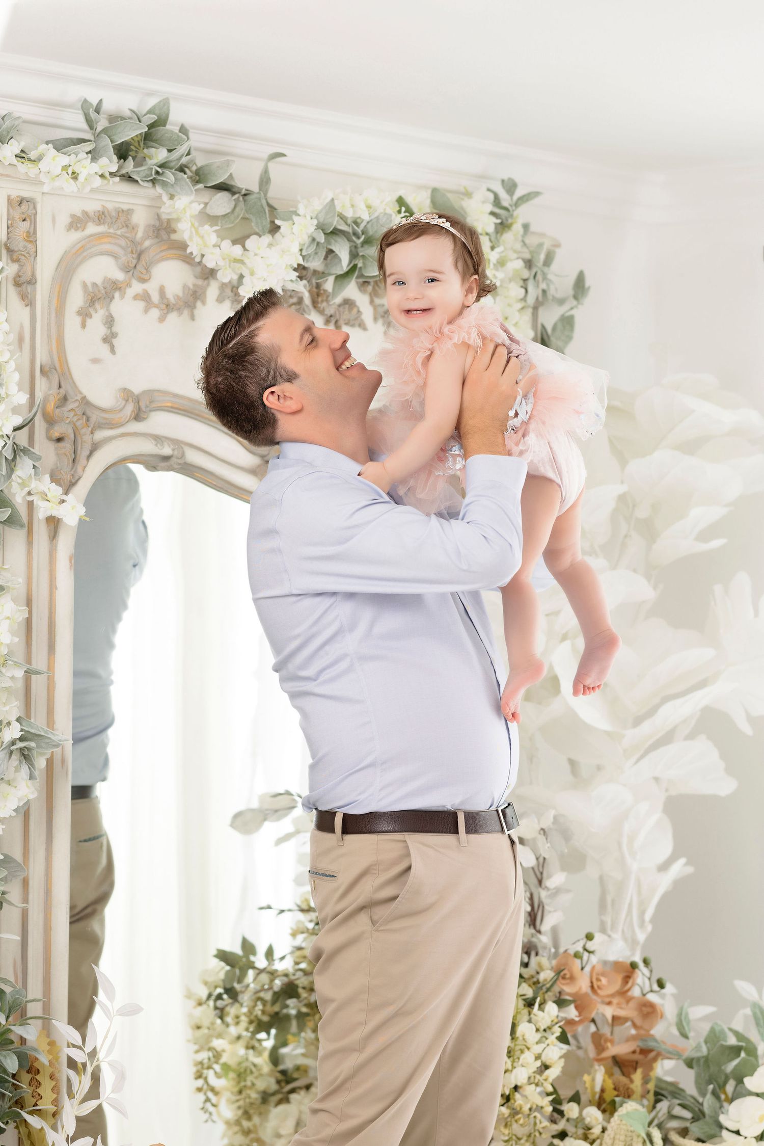 Joyful moment captured against elegant floral backdrop in white studio.