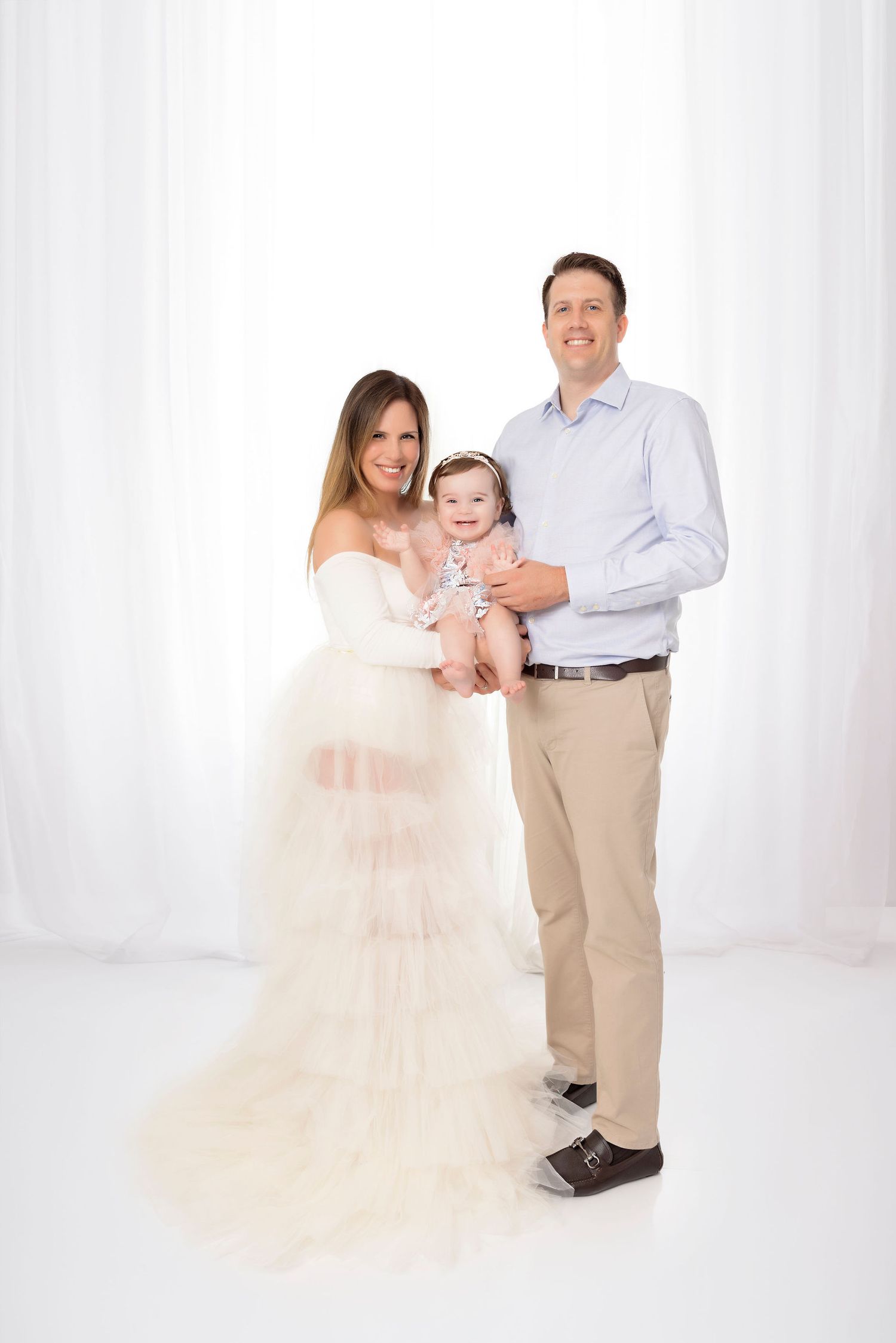 Studio portrait featuring elegant tulle gown and coordinated family outfits.
