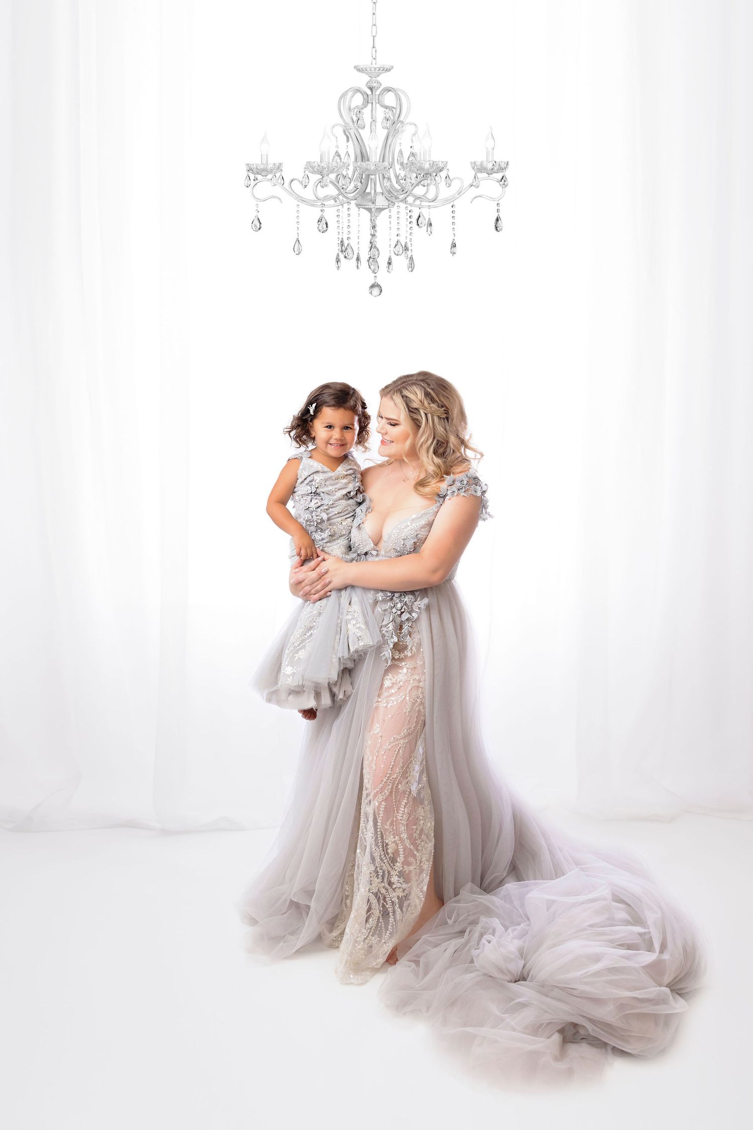 Ethereal studio portrait with crystal chandelier and flowing grey tulle gowns.