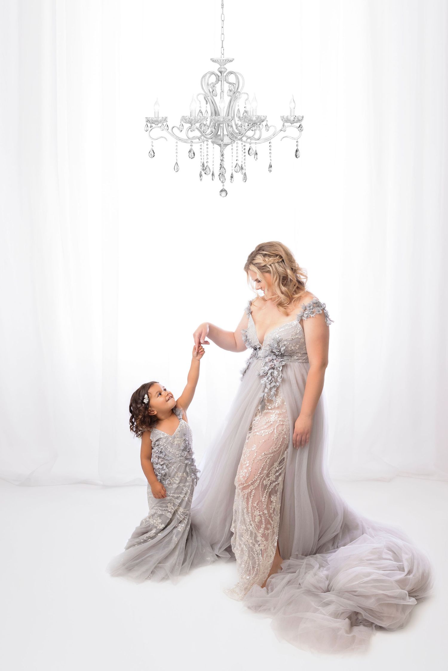 Sweet studio portrait under crystal chandelier with matching grey dresses.