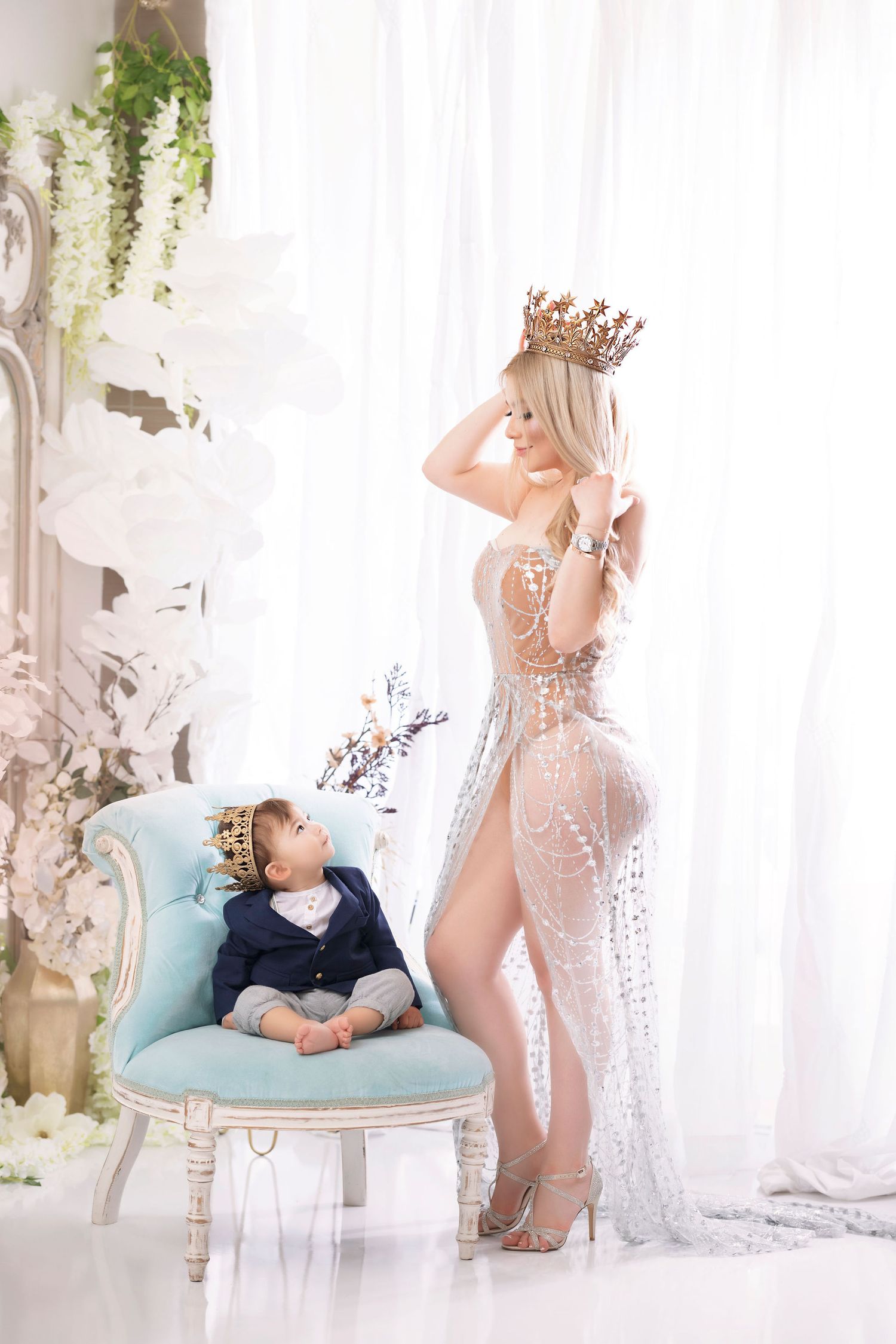 Dreamy portrait with crown and sheer gown next to vintage blue chair.