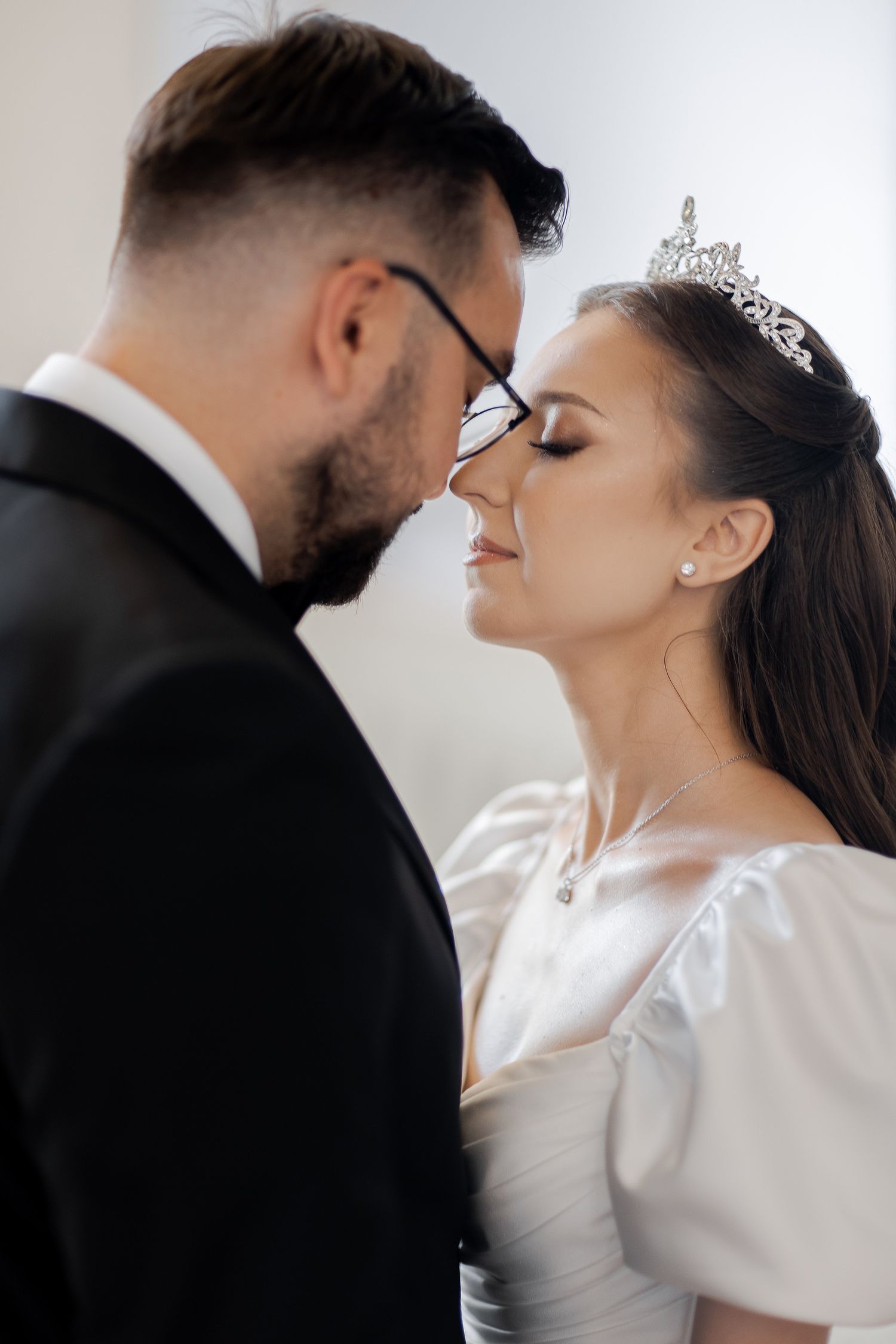 Intimate wedding portrait of couple sharing a tender moment with foreheads touching.