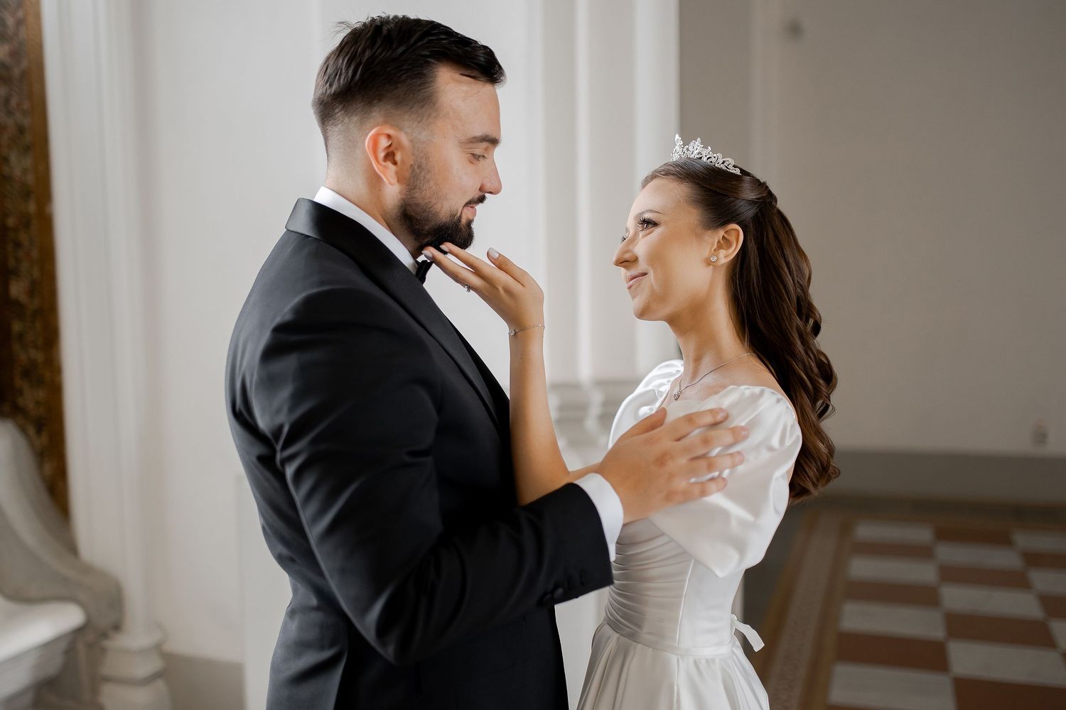 Joyful wedding couple sharing intimate moment in elegant white interior.