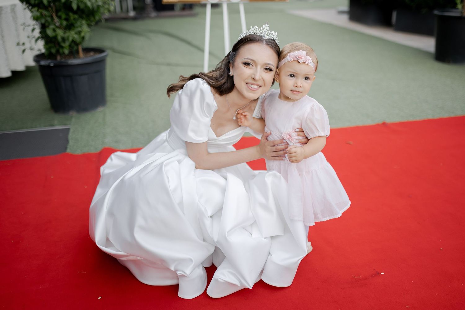 A sweet wedding moment captured on a red carpet with matching white dresses.