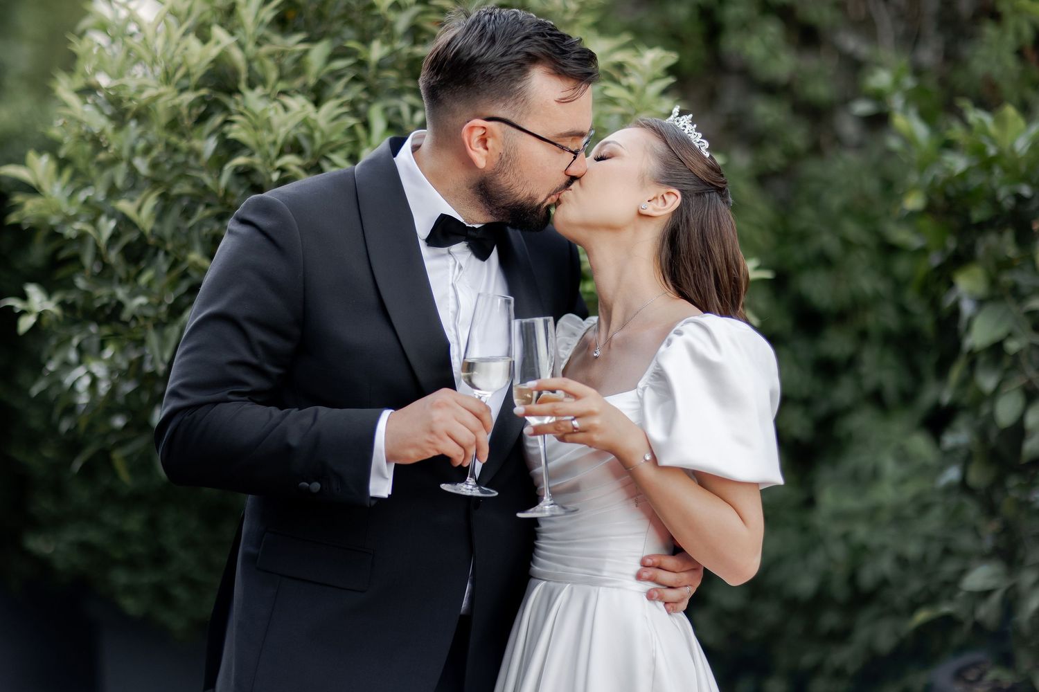 A romantic champagne toast between newlyweds in a garden setting.