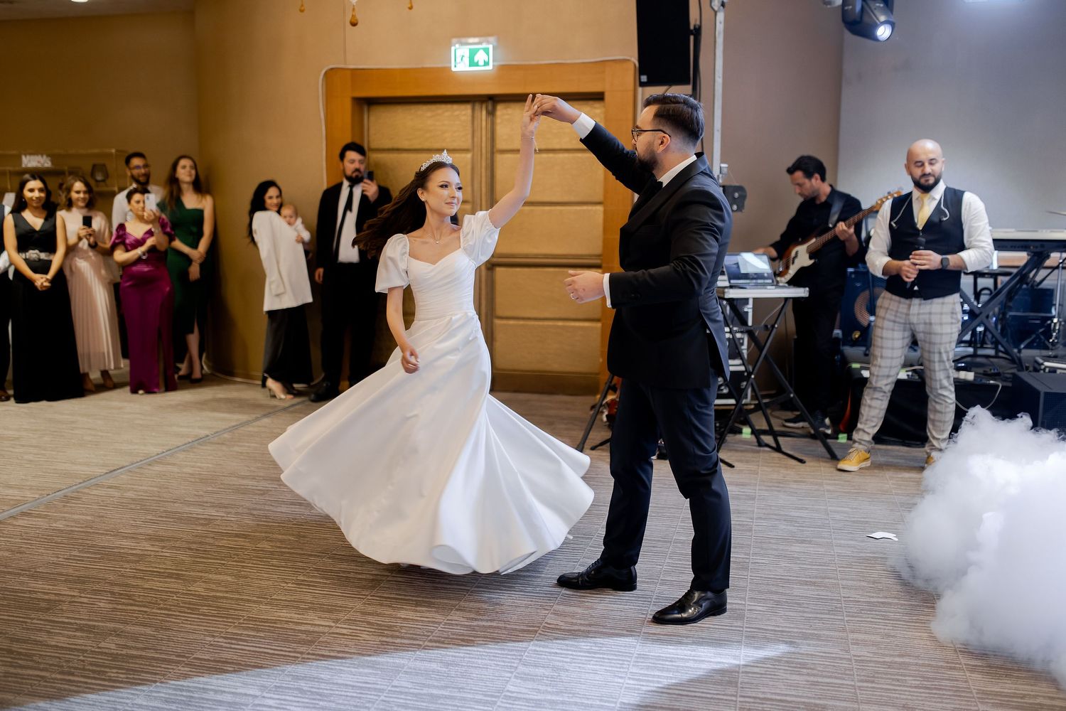 Couple performs first dance at wedding reception while guests watch from the sidelines.