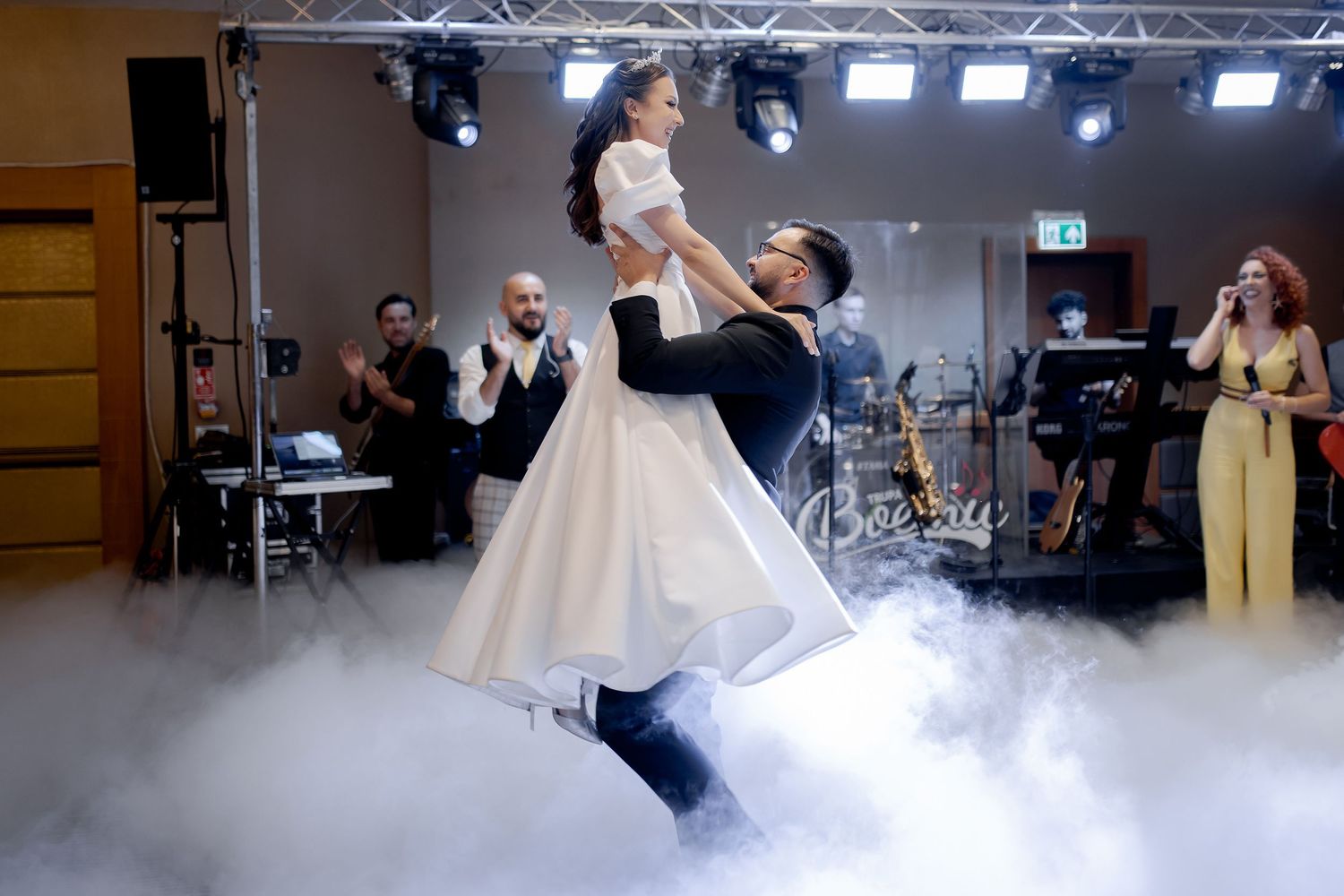 Dramatic lift during wedding first dance with fog effects and band in background.