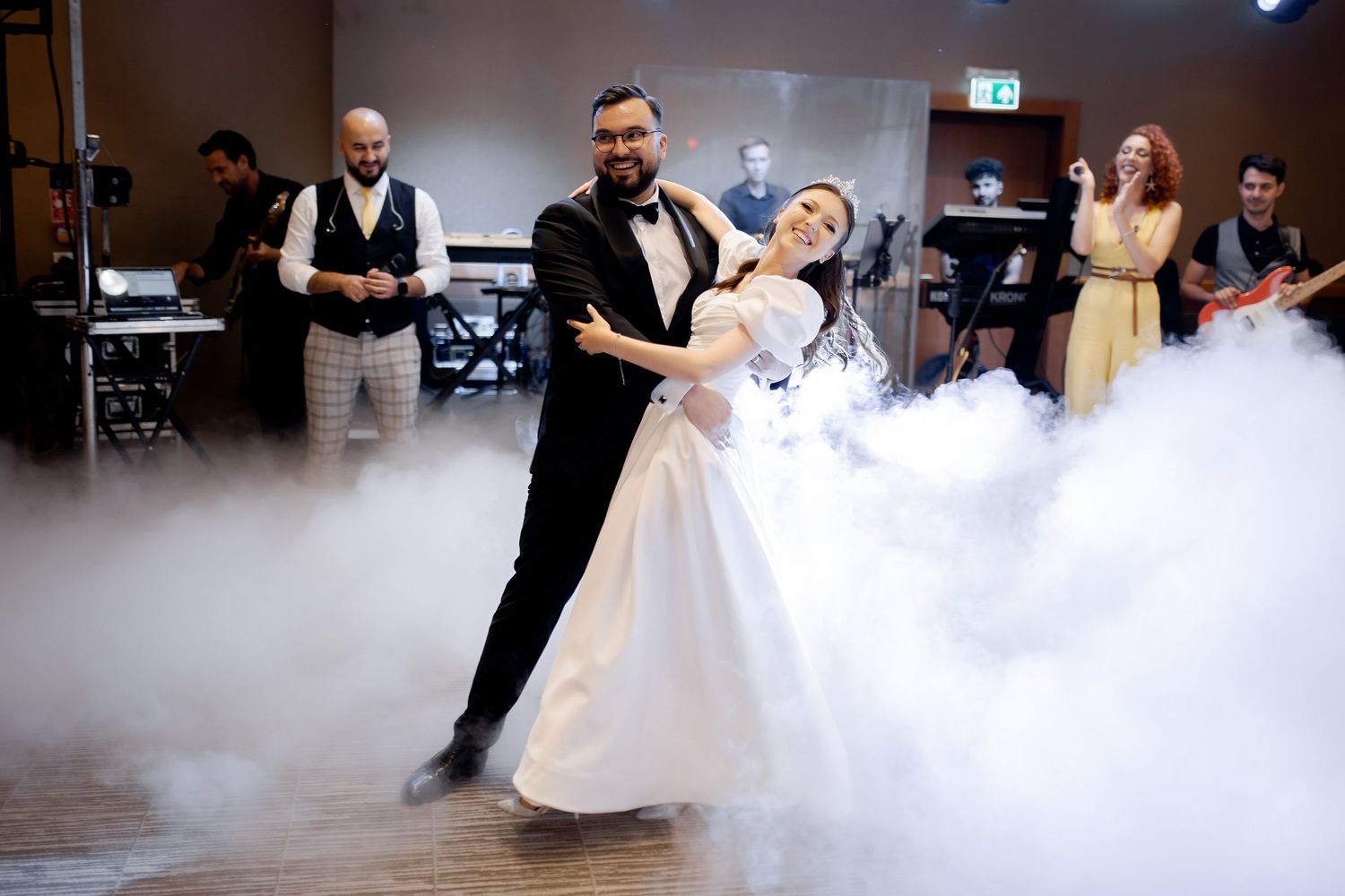 A couple performs their first dance in a cloud of fog on a wedding reception dance floor.