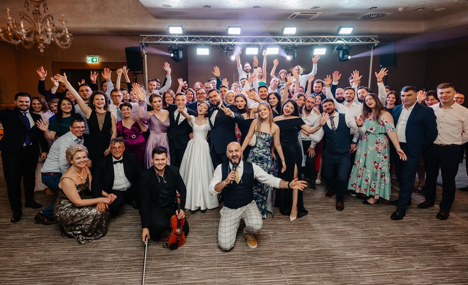 A large group celebrates at a wedding reception with fog on the dance floor.