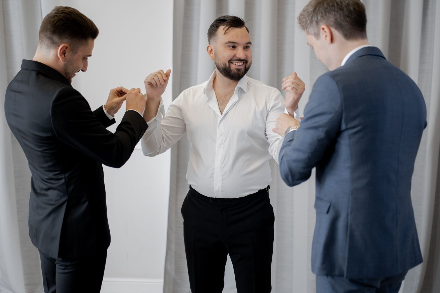 Three people in formal attire celebrate together in a bright indoor setting.