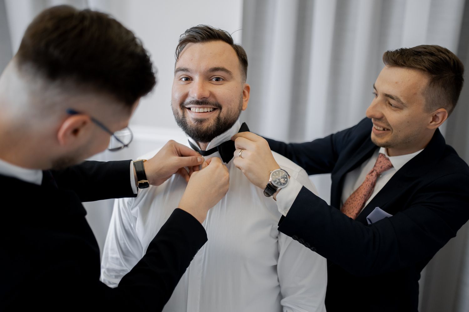 Group helping to adjust formal attire during wedding preparations.