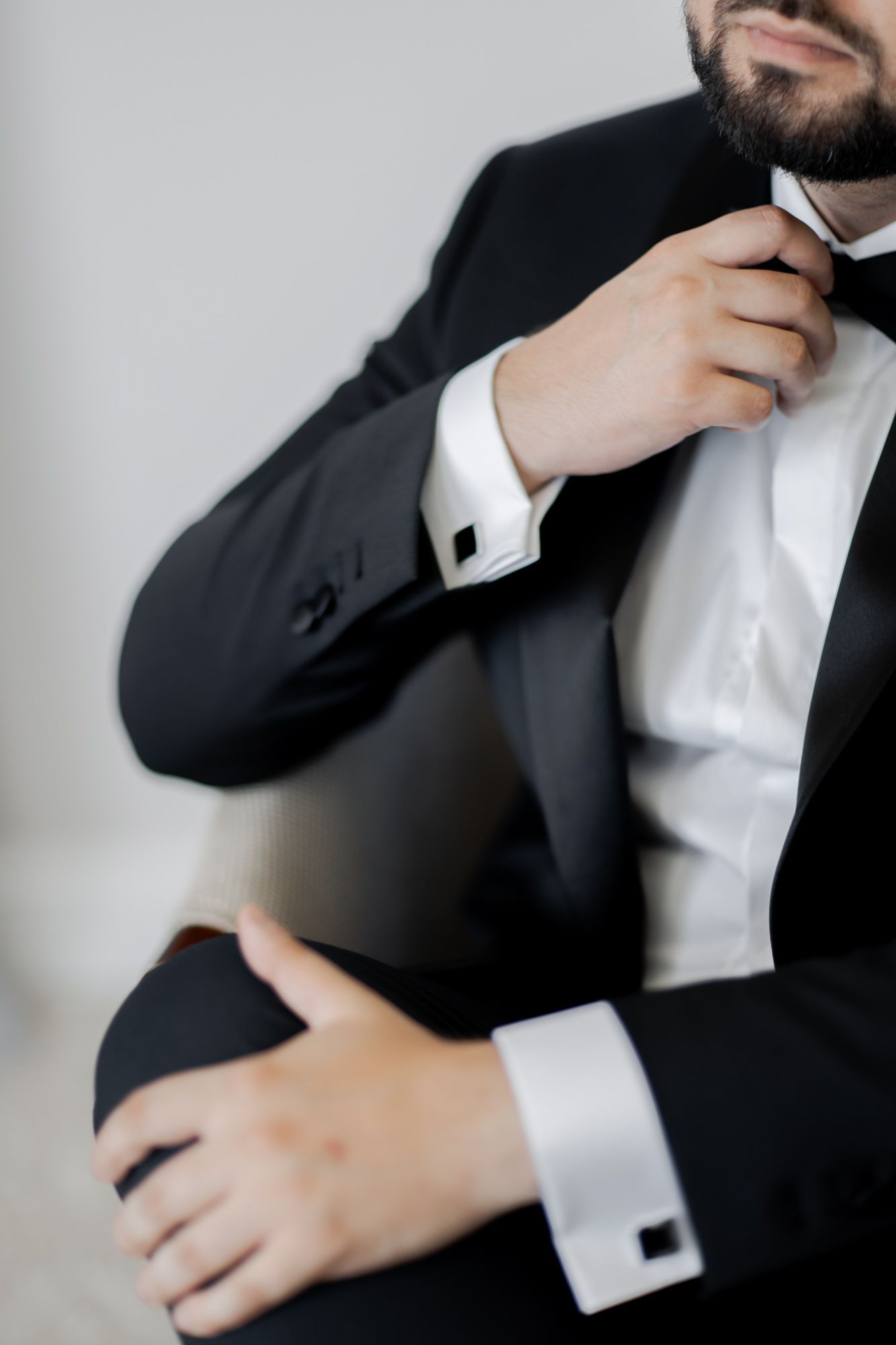 Close-up of formal attire showing tuxedo jacket, white shirt, and cufflinks.