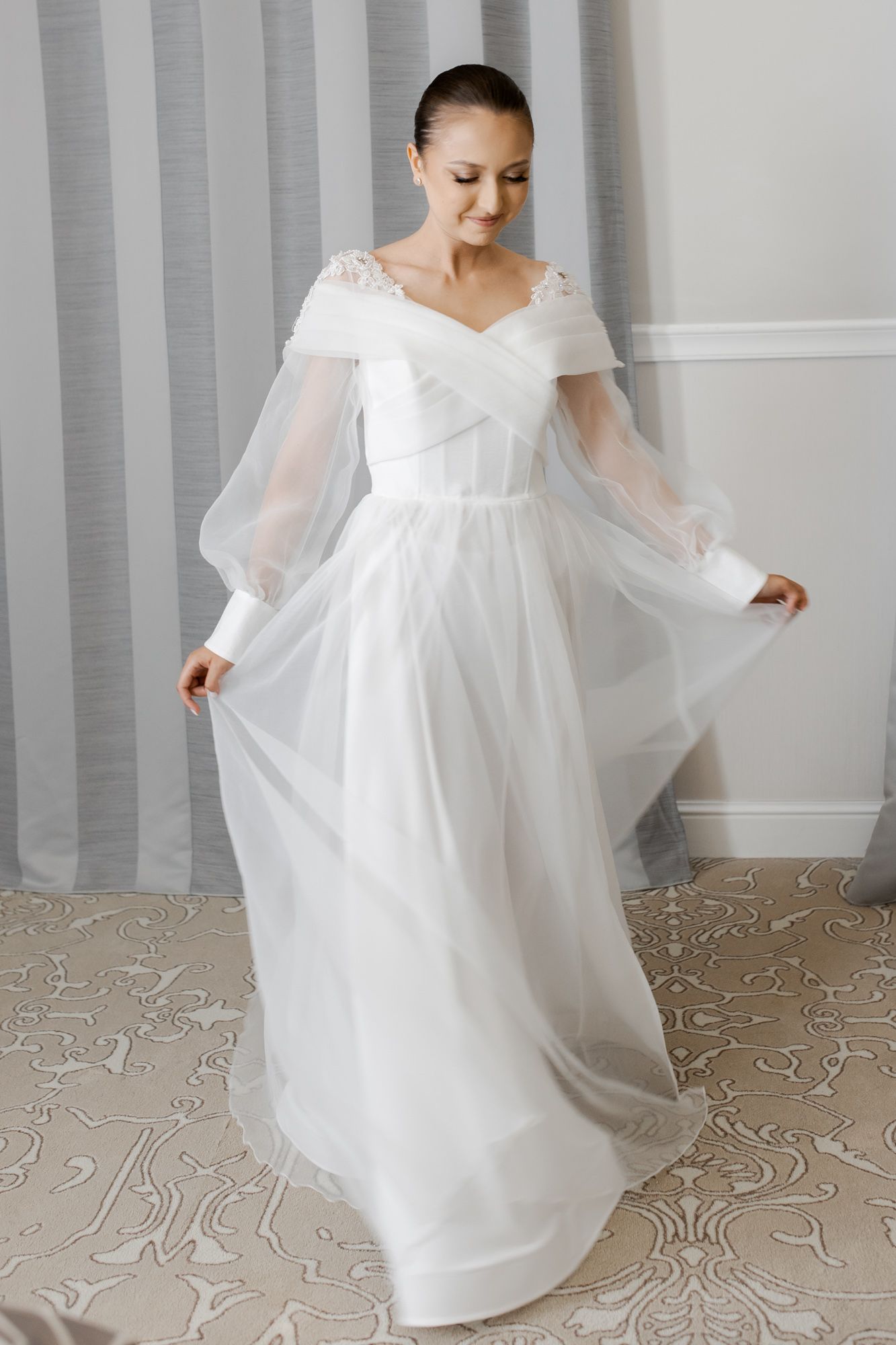 Ethereal white wedding gown with sheer sleeves and sweetheart neckline worn in elegant pose.