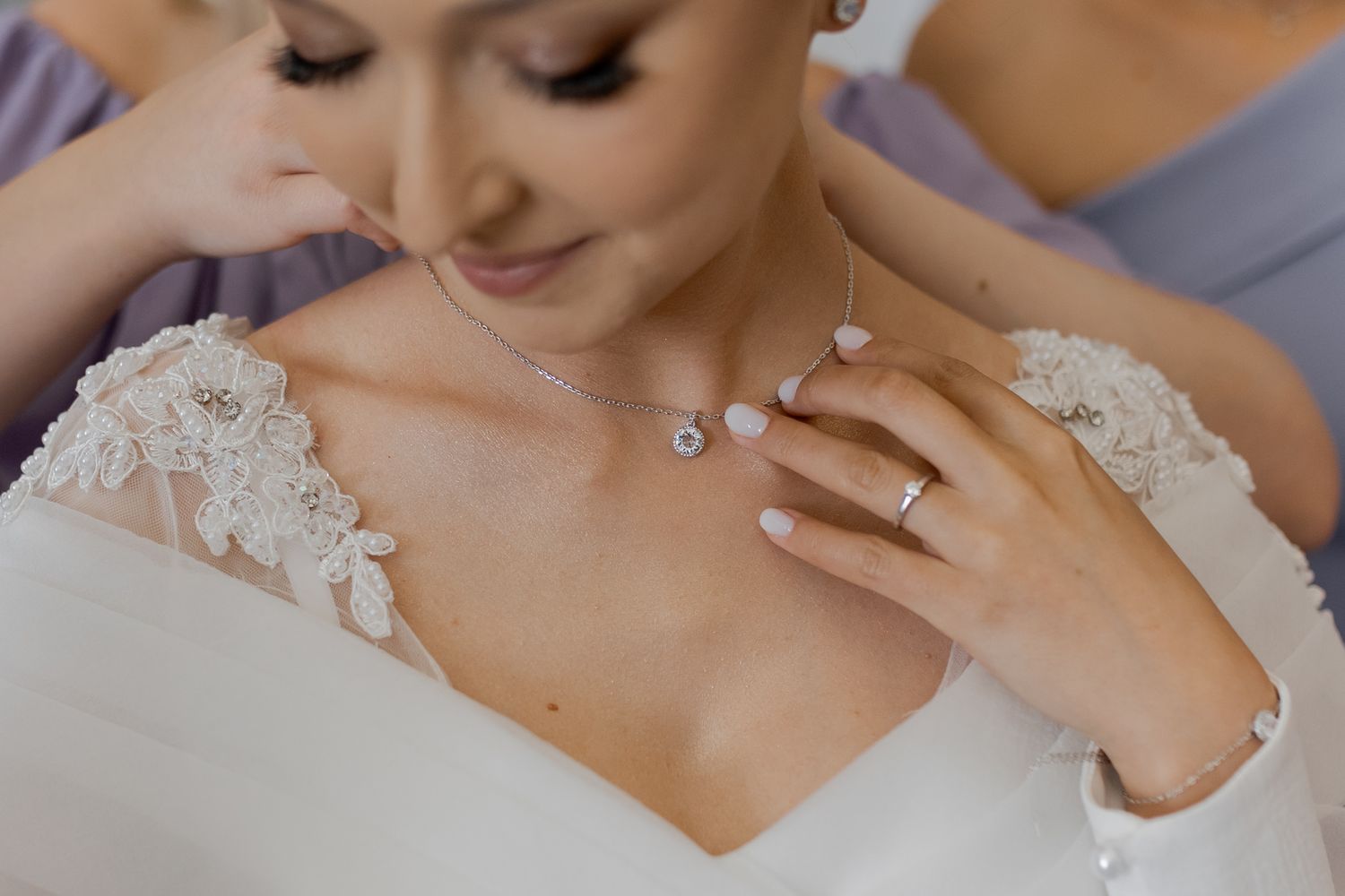 Close-up of delicate bridal jewelry and lace details on a wedding dress.