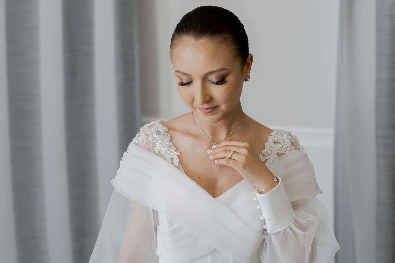 Elegant bridal portrait featuring a white lace wedding dress with long sleeves.