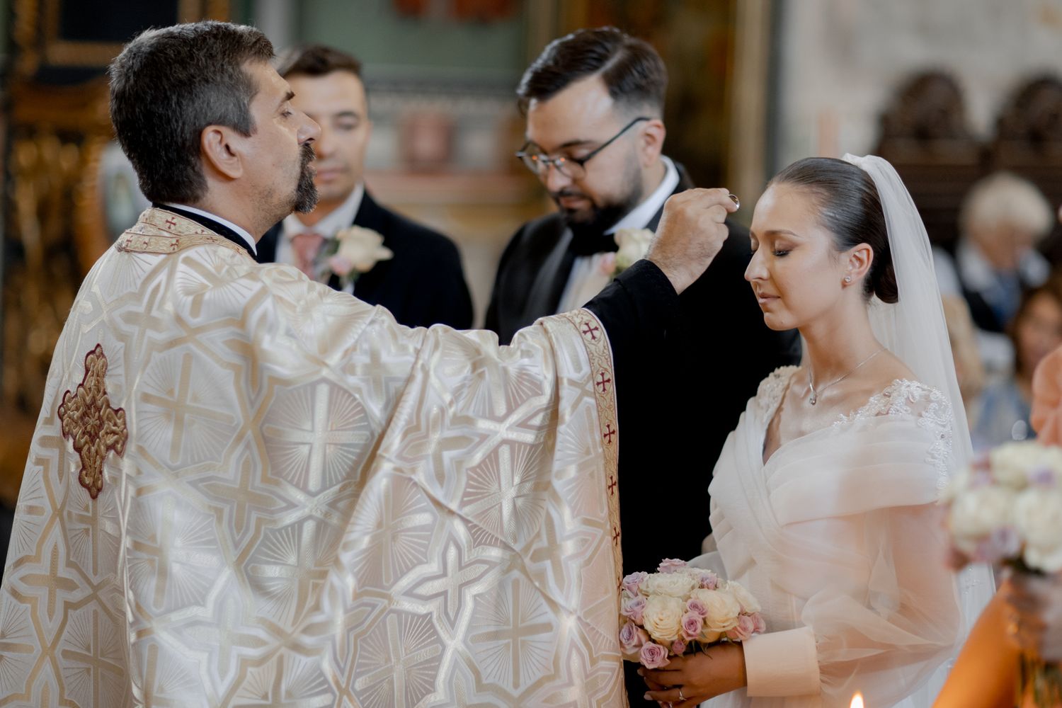 A priest in ornate robes conducts a traditional wedding ceremony in an elegant church setting.