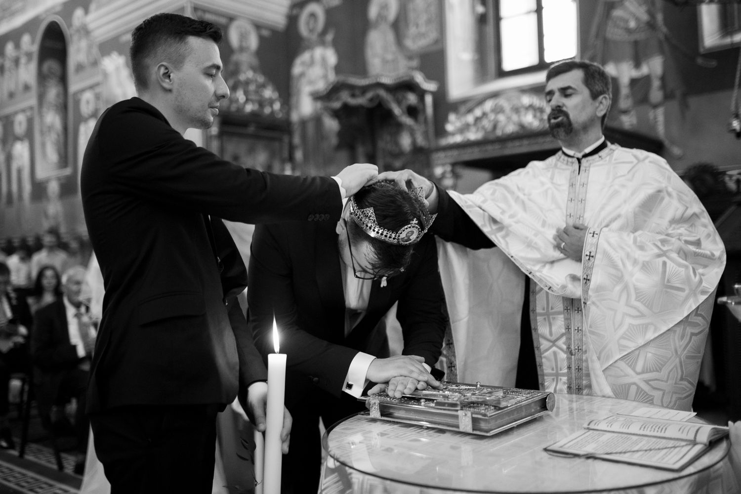 Black and white photo of orthodox priest performing traditional wedding blessing ceremony.