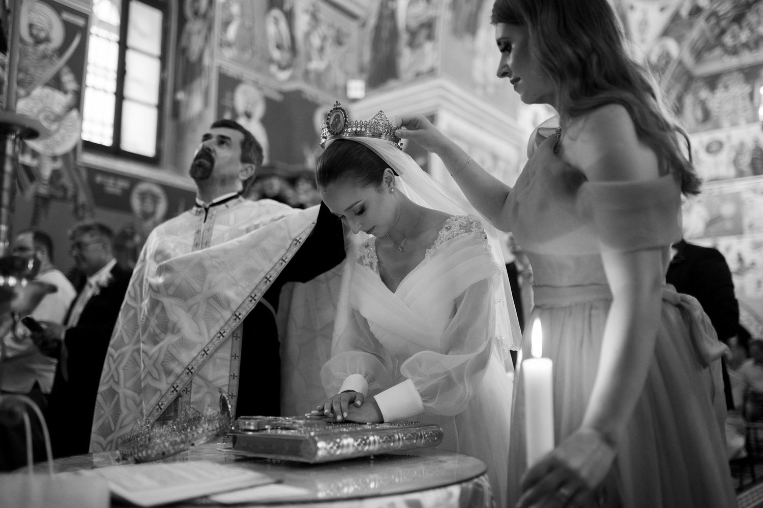 Black and white image of wedding ceremony with priest and attendants at altar.