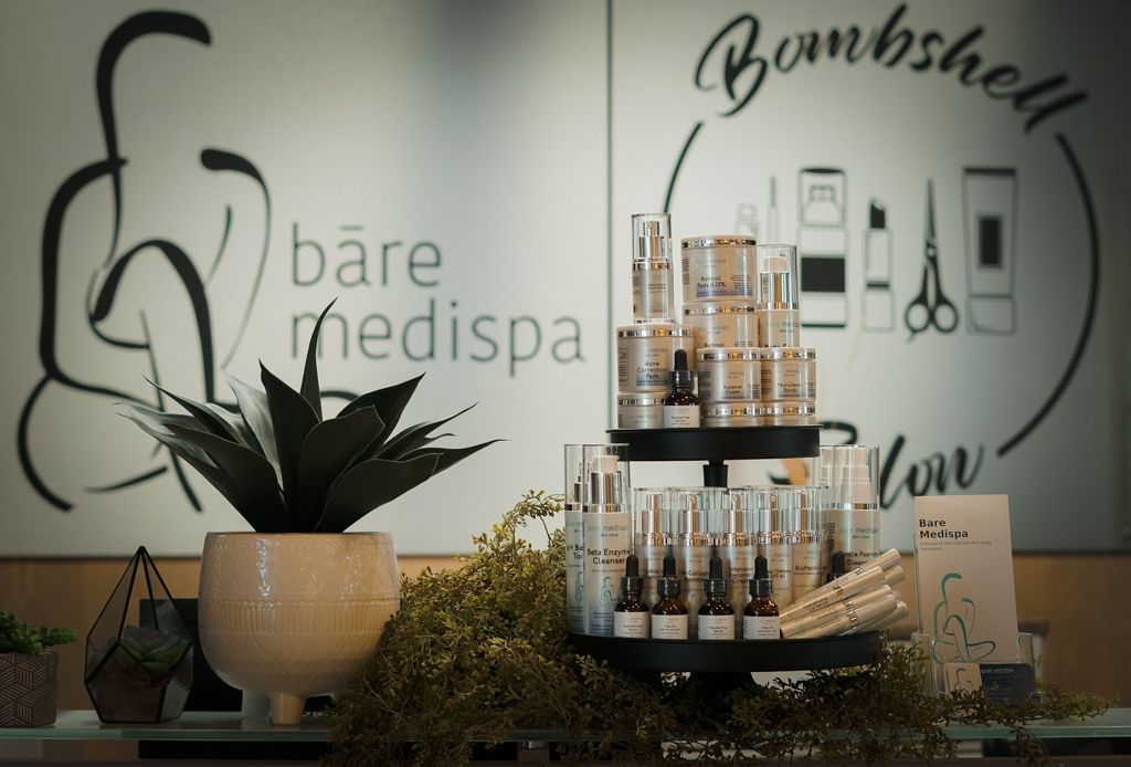 Bare Medispa skincare products displayed on counter with Bombshell Salon branding in background.