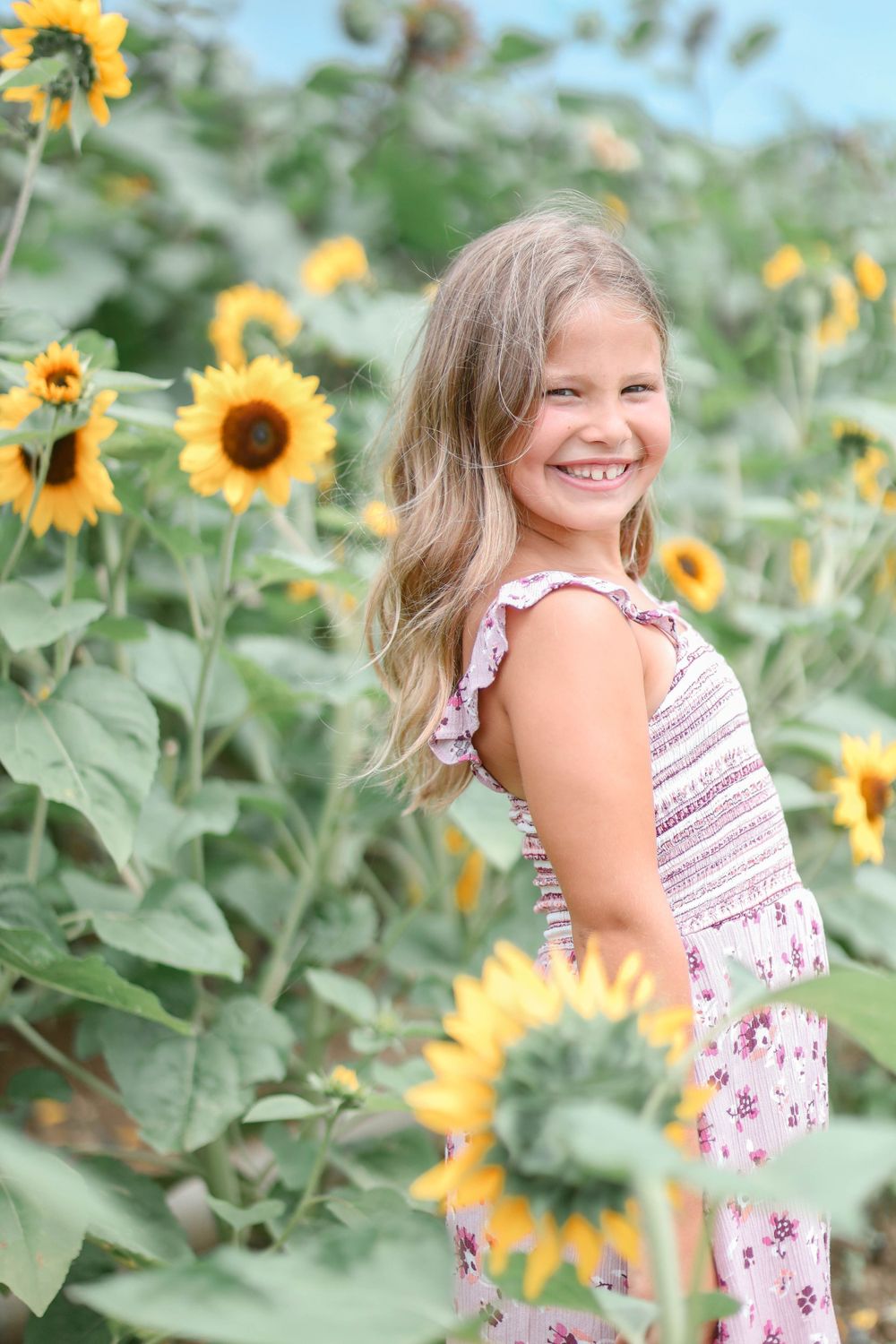 Smiling girl poses in sunflower field
