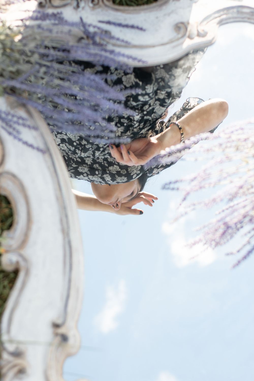 An ornate vintage mirror frame photographed from below against a blue sky with soft wispy clouds.