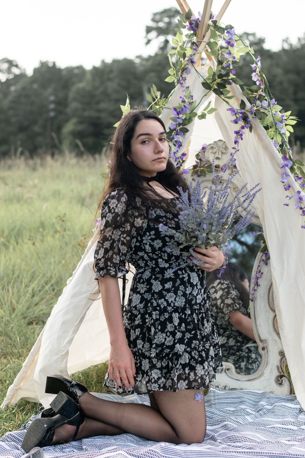 A floral decorated mirror setup with white fabric creates a romantic outdoor scene in a meadow.