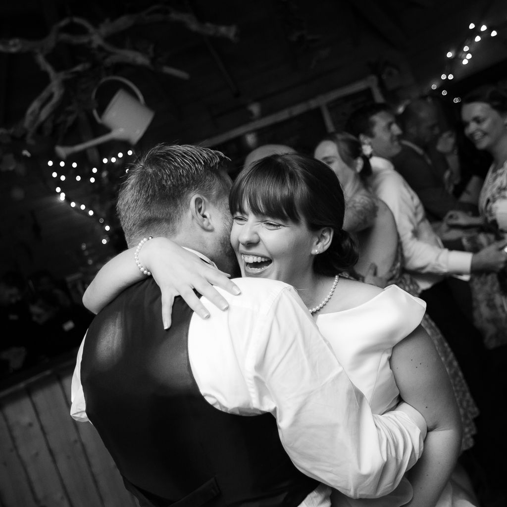 Couples dancing together at a dimly lit reception with string lights overhead.