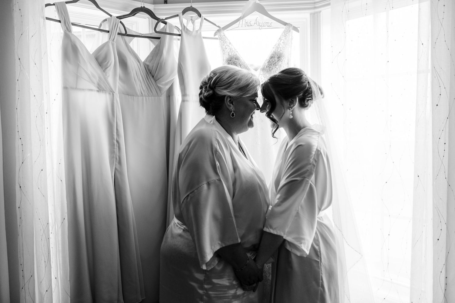 Black and white photo showing wedding morning preparations by a window.