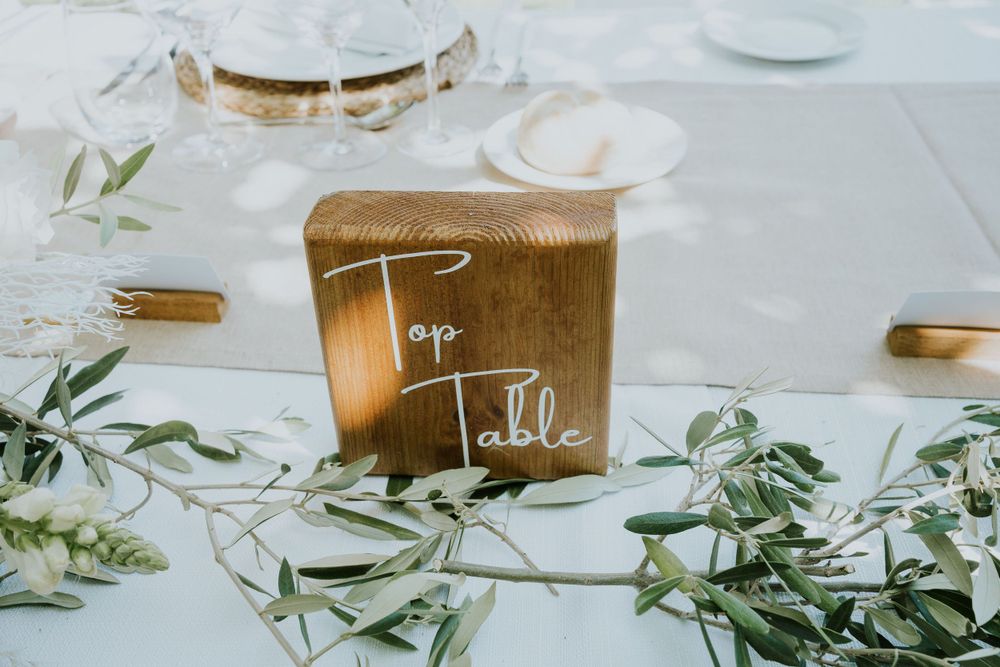 Gold wedding card box decorated with greenery on white tablecloth.