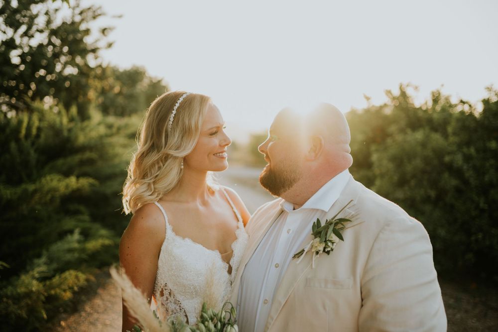 Golden hour portrait of couple in wedding attire with sunlight filtering through trees.