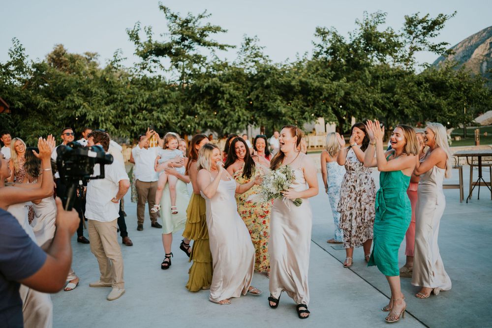 Wedding guests dance and celebrate on an outdoor patio during sunset festivities.