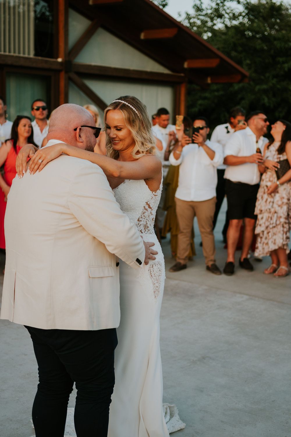 A couple shares their first dance surrounded by guests at an outdoor wedding reception.