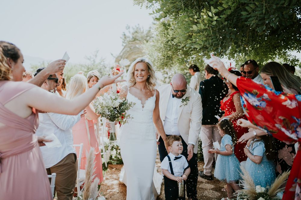 Wedding recessional with guests throwing confetti as couple walks through.